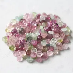 En hög med små, fasetterade turmaliner i olika färger, från rosa till grönt. Dessa stenar sägs ha helande turmalin egenskaper.