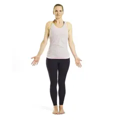 Krigaren yoga: kvinna i randig topp och mörka leggings står med armarna utåt, redo att möta dagen med styrka och lugn.