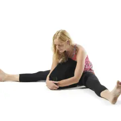 Kvinna i yin yoga-position med benen isär och en kudde mot bröstet. Utforska yin yoga effekter för ökad rörlighet och lugn.