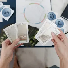 Händer håller tarotkort med symboler för sjunde huset astrologi. En astrologisk karta och stjärntecken syns i bakgrunden.