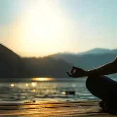 Person mediterar vid solnedgången, en lugn scen som kan inspirera till en ayurveda utbildning.