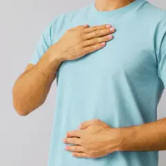 En person med händerna på bröstet och magen, som om det är svårt att andas djupt på grund av stress.