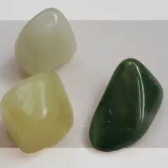 Three smooth, polished jade stones: one pale green, one light yellow-green, and one dark green.