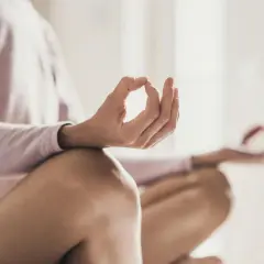 En person sitter i meditationsställning, med händerna i mudra. En bild som visar meditation effekter av lugn och ro.