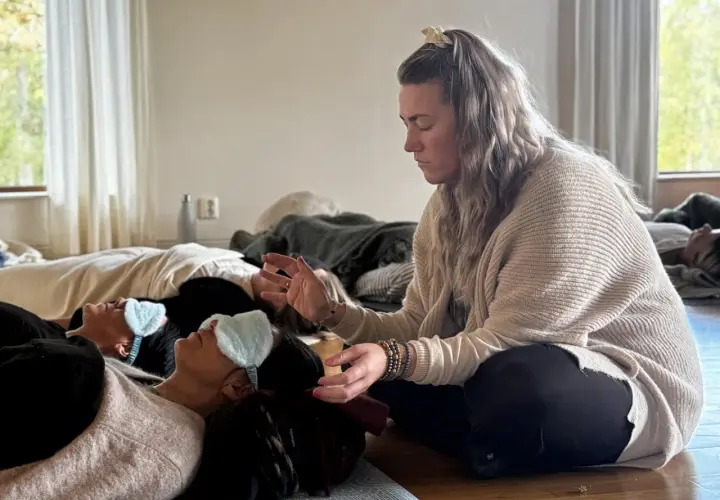 En kvinna leder en breathwork utbildning. Deltagare ligger på golvet med sovmaskar, redo att utforska andningens kraft.