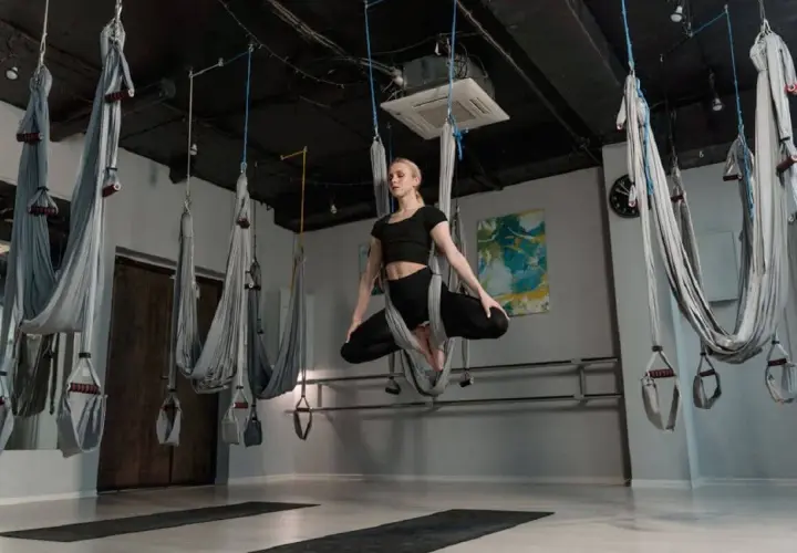 Kvinna utövar flying yoga i en studio med hängmattor.
