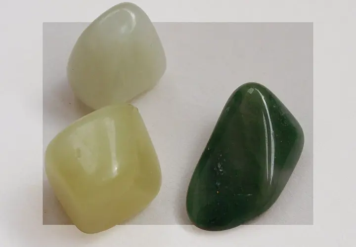 Three smooth, polished jade stones: one pale green, one light yellow-green, and one dark green.