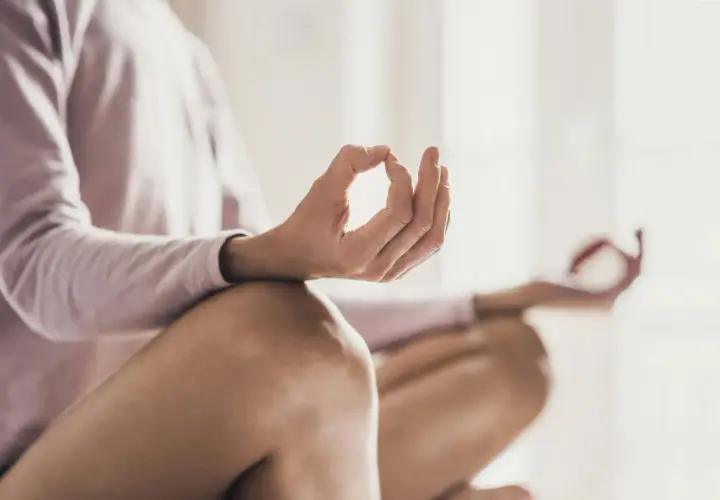 En person sitter i meditationsställning, med händerna i mudra. En bild som visar meditation effekter av lugn och ro.