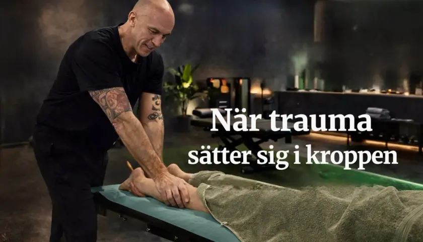 En man med tatueringar masserar en persons ben på en brits. Texten "När trauma sätter sig i kroppen" antyder en behandling för fysiska effekter av trauma.
