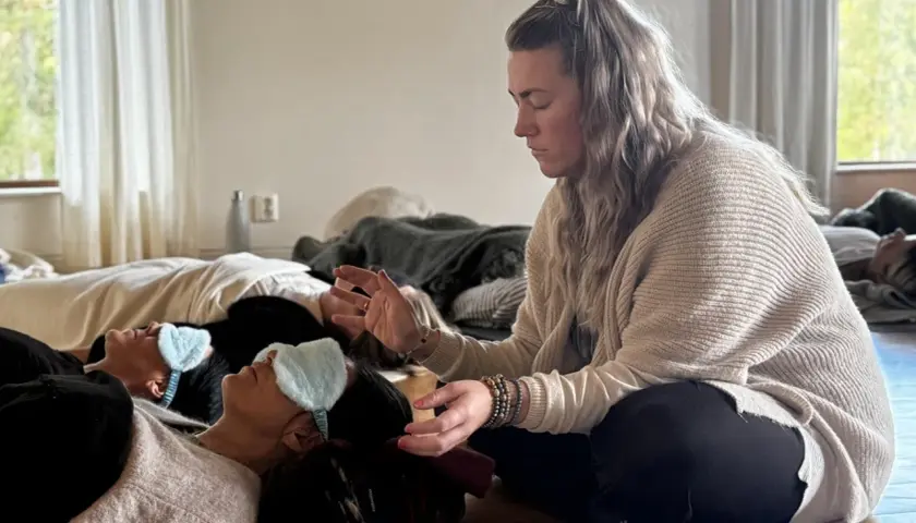 En kvinna leder en breathwork utbildning. Deltagare ligger på golvet med sovmaskar, redo att utforska andningens kraft.