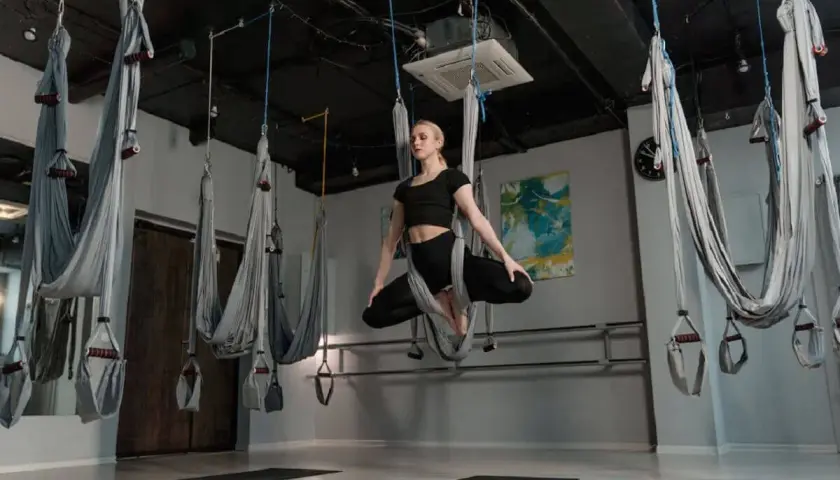 Kvinna utövar flying yoga i en studio med hängmattor.