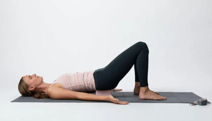 Kvinna i brygga med block under svanskotan, en lugnande position som kan stödja **yin yoga viktminskning** genom avslappning och stressreducering.