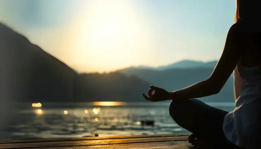 Person mediterar vid solnedgången, en lugn scen som kan inspirera till en ayurveda utbildning.