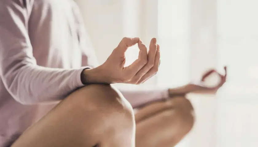 En person sitter i meditationsställning, med händerna i mudra. En bild som visar meditation effekter av lugn och ro.