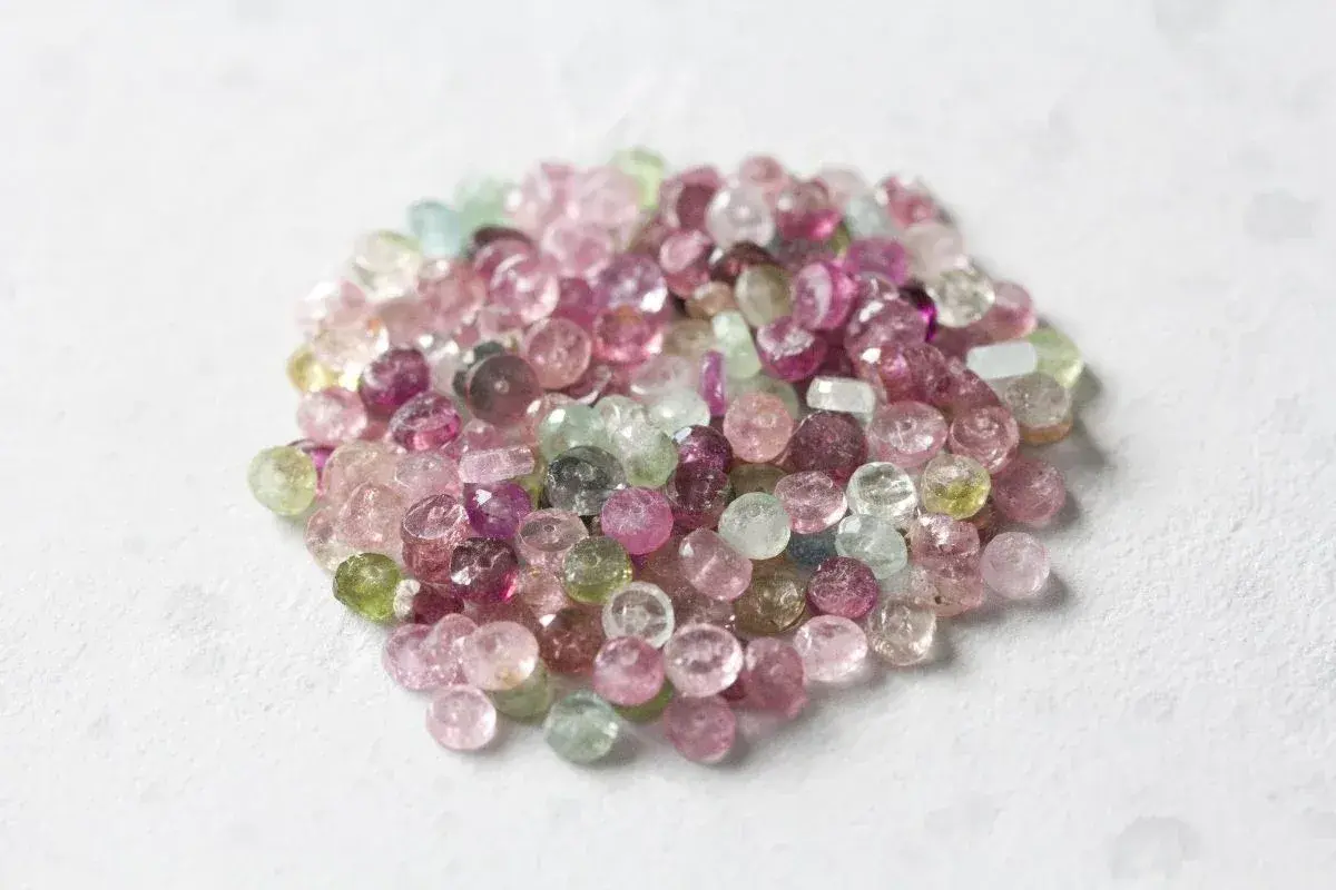 En hög med små, fasetterade turmaliner i olika färger, från rosa till grönt. Dessa stenar sägs ha helande turmalin egenskaper.