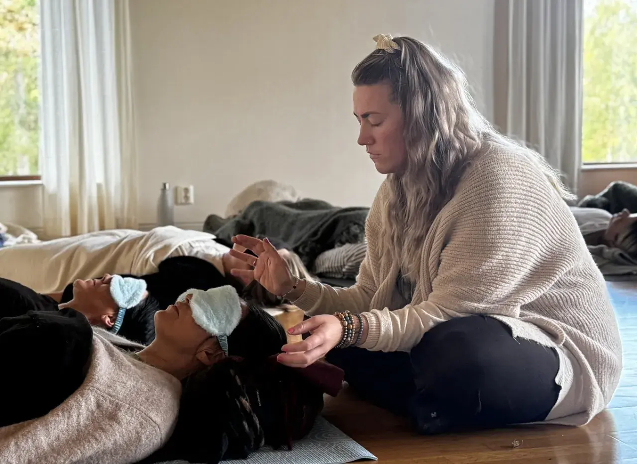 En kvinna leder en breathwork utbildning. Deltagare ligger på golvet med sovmaskar, redo att utforska andningens kraft.