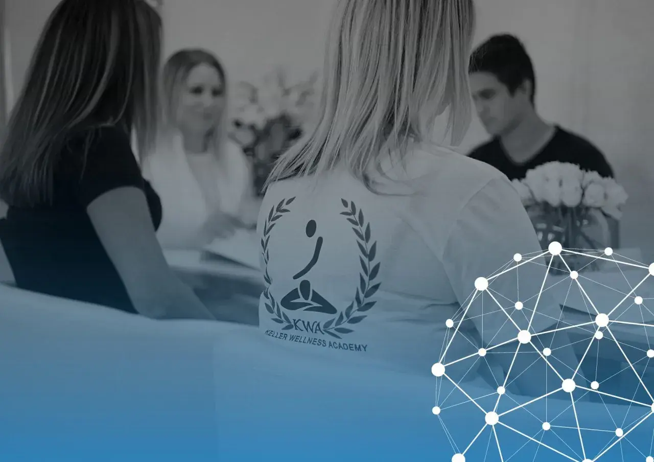 Personer samlade för fascia utbildning. En person bär en t-shirt med logotypen för Keller Wellness Academy.
