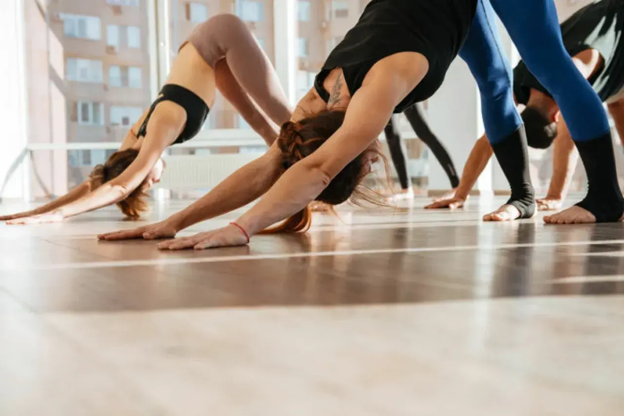 Människor i en yogaklass utför nedåtgående hund, en position som främjar yoga och inre balans.