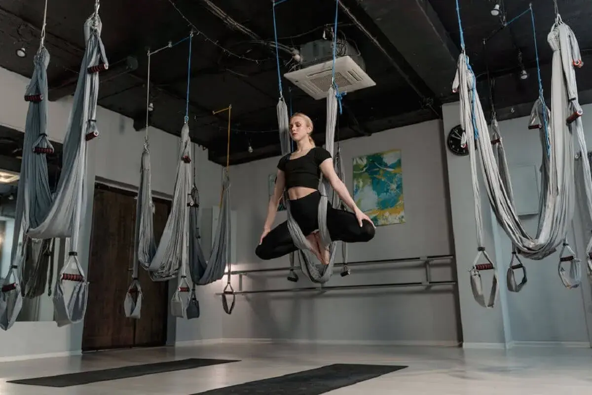 Kvinna utövar flying yoga i en studio med hängmattor.