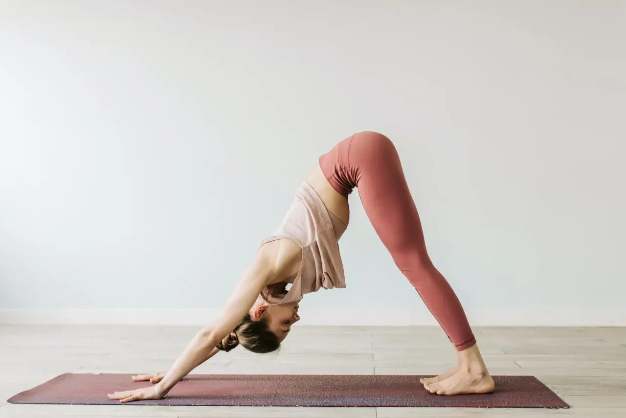 En kvinna utför en hund som sträcker sig nedåt-position under yoga.