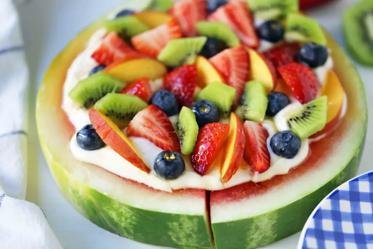 En saftig vattenmelonbotten toppad med kr&auml;mig frosting och f&auml;rsk frukt som jordgubbar, bl&aring;b&auml;r, kiwi och persika. En perfekt nyttig t&aring;rta f&ouml;r sommaren.