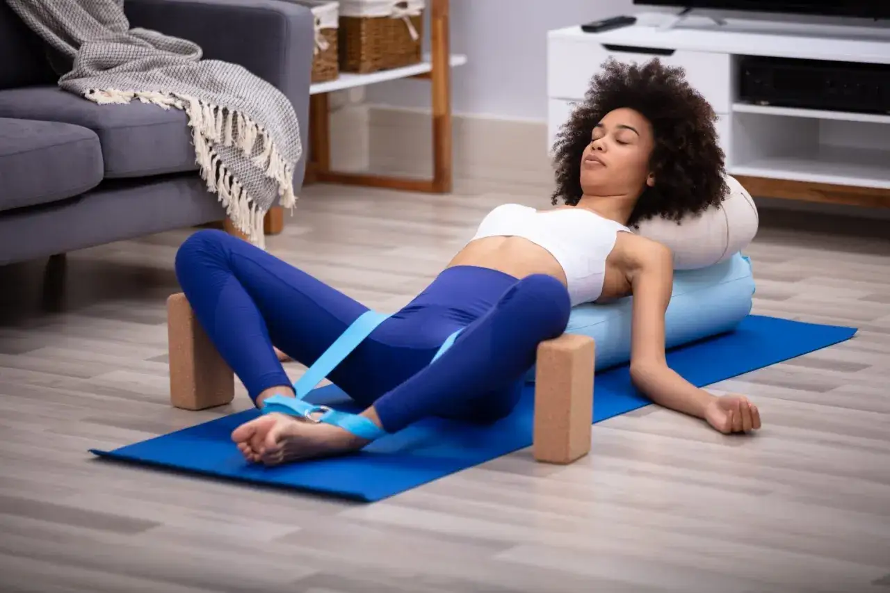Kvinna ut&ouml;var fascia yoga i en bekv&auml;m position med st&ouml;d av bolster och block.