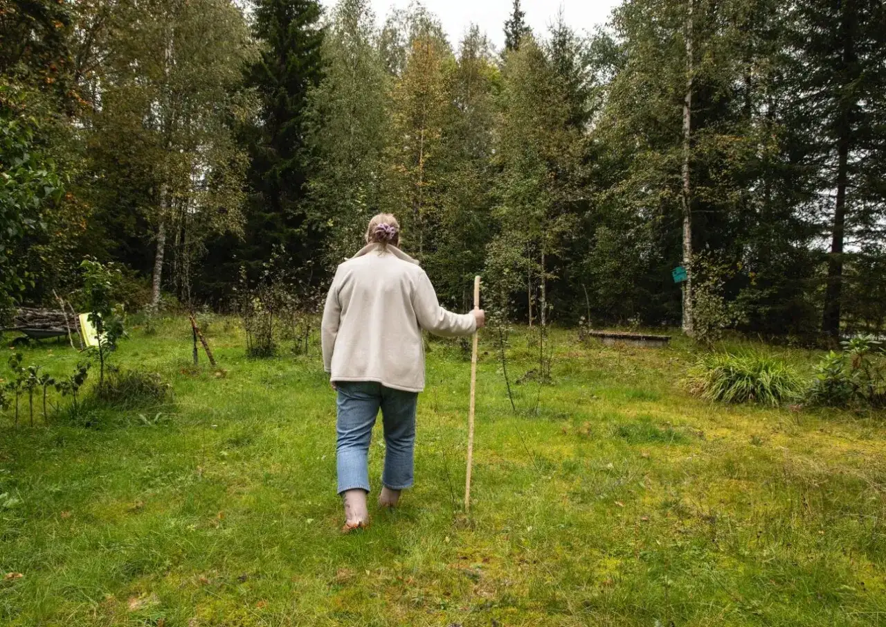 En person med k&auml;pp g&aring;r genom en gr&ouml;nskande &auml;ng, omgiven av tr&auml;d. Kanske letar personen efter platser som liknar bl&aring; zoner i Sverige, d&auml;r man kan finna lugn och ro.