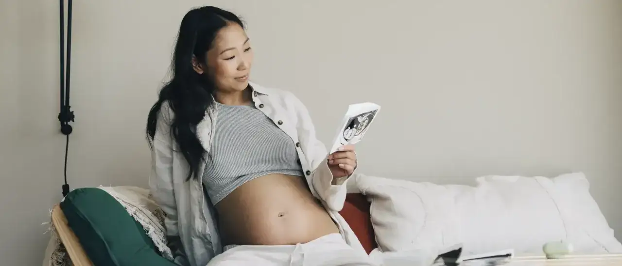En gravid kvinna tittar p&aring; ett ultraljudsfoto, lycklig i sin andra trimestern.