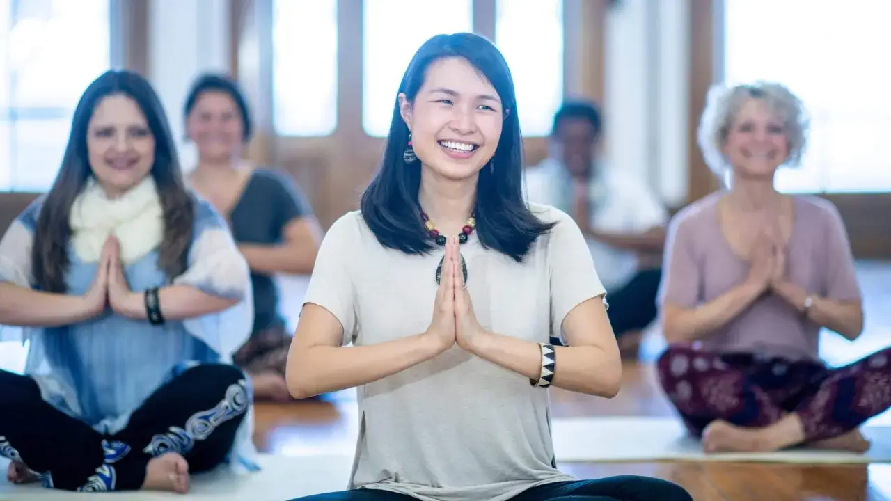 En grupp människor sitter i lotusställning och ler under en kundalini yoga-klass.