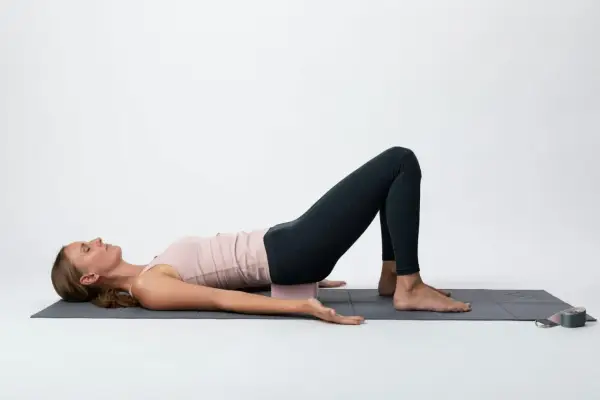 Kvinna i brygga med block under svanskotan, en lugnande position som kan stödja **yin yoga viktminskning** genom avslappning och stressreducering.